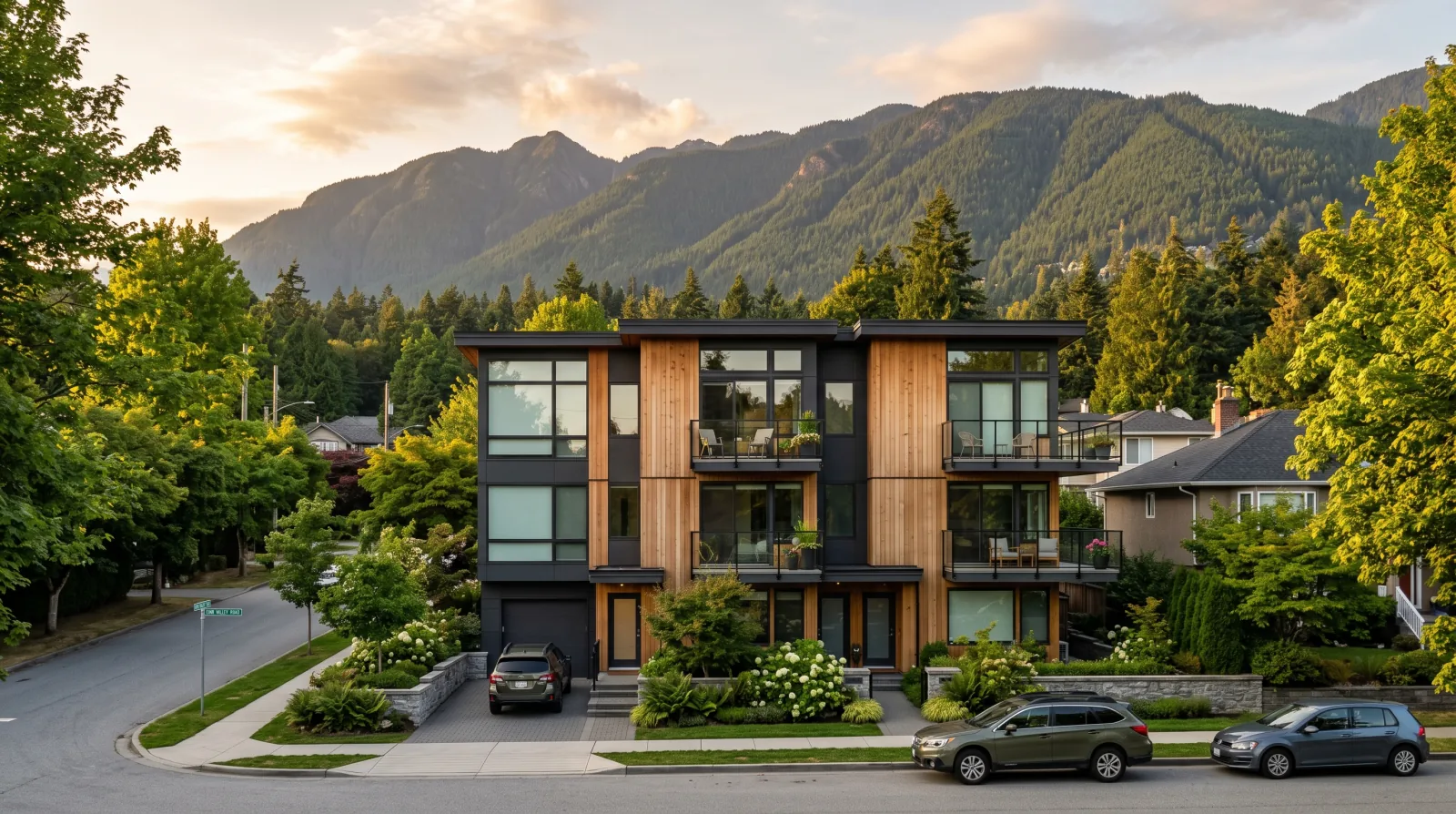 A three-storey multiplex on a leafy street in Lynn Valley, District of North Vancouver, with the North Shore mountains behind